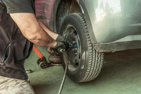 Mechanic using an electric screwdriver to remove a wheel in a garage Stock Photos