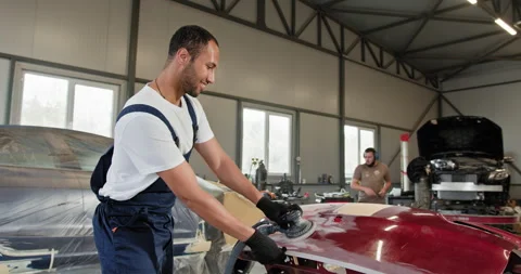 Mechanic Using Grinding Unit on Red Car Bumper at Repair Station Stock Footage 276565385