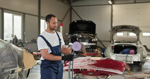 Mechanic Using Grinding Unit on Red Bumper at Auto Repair Shop Stock Footage 276568642