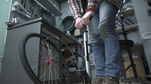 Mechanic using hand pump to inflate bicycle wheel. Repairman pump tire in Stock Footage 155001303
