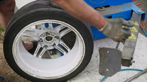 Mechanic using hydraulic or mechanical press to remove used tire from a rim Stock Footage 129510497