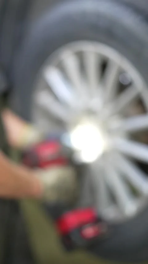 Mechanic Using Impact Wrench on Car Wheel Bolt Removal in Auto Workshop Setting Stock Footage 346119831