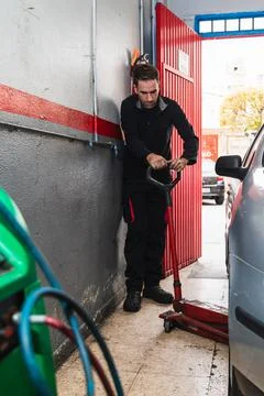 Mechanic using a jack to lift the car. Automobile mechanics concept Stock Photos