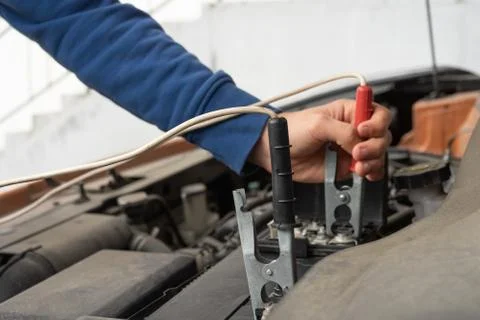 A mechanic using jumper cables to start a car battery. Stock Photos
