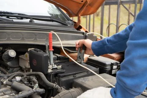 A mechanic using jumper cables to start a car battery. Stock Photos