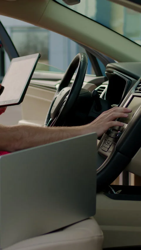 Mechanic using laptop to analyze vehicle performance data while seated in car Stock Footage 318029327