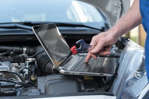 Mechanic using laptop for checking car engine Stock Photos