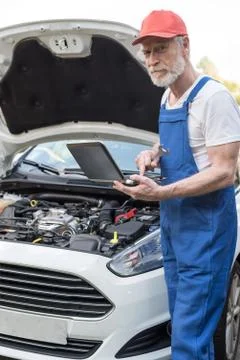 Mechanic using laptop for checking car engine Fotos de archivo