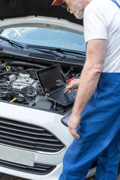 Mechanic using laptop for checking car engine Foto stock
