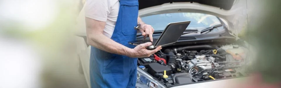 Mechanic using laptop for checking car engine 스톡 사진
