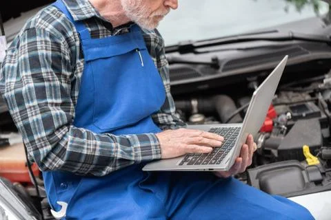 Mechanic using laptop for checking car engine Foto stock