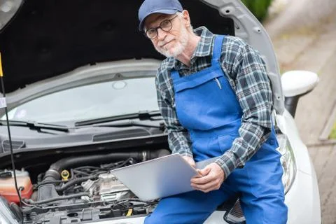 Mechanic using laptop for checking car engine Stock Photos