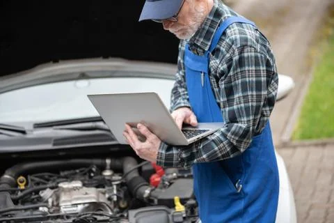 Mechanic using laptop for checking car engine Foto stock
