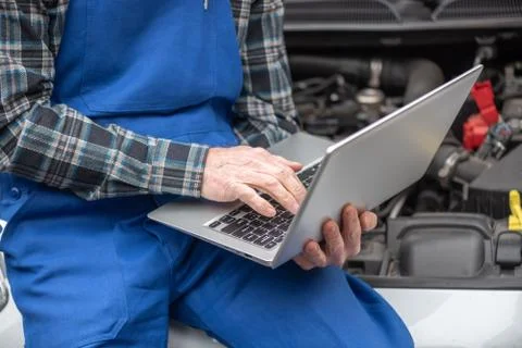 Mechanic using laptop for checking car engine 写真素材