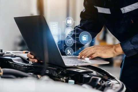 Mechanic using laptop checking up on car engines parts for fixing and repair. Fotos de archivo