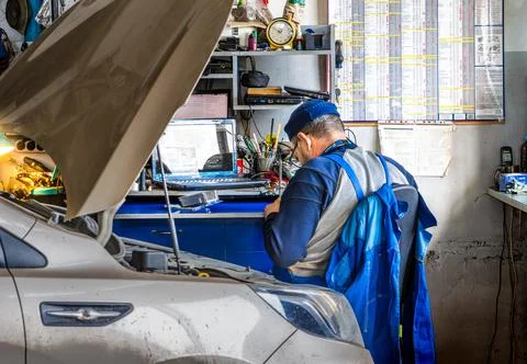 Mechanic using laptop for engine diagnostics in service center office Stock Photos