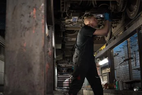 Mechanic using light to inspect a subway car Stock Photos