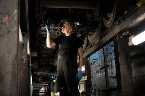 Mechanic using light to inspect a subway car Stock Photos