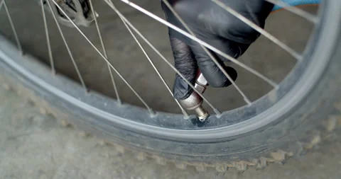Mechanic using a manual air pump to carefully inflate a bicycle tire. Stock Footage 311665398