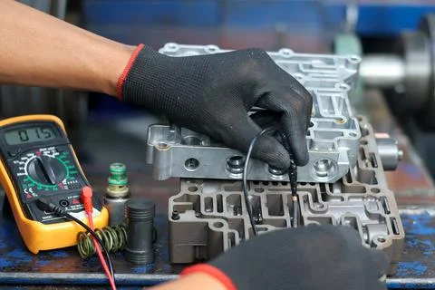 Mechanic using a multimeter to test an automatic transmission valve body. Stock Photos