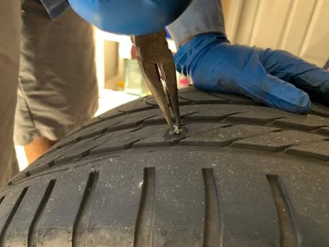 Mechanic Using Pliers to Remove Nail in Tire Stock Photos