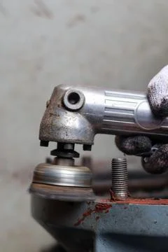 Mechanic using a pneumatic grinder on a machine part. Stock Photos