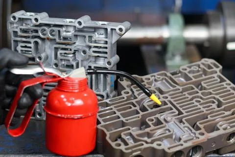 Mechanic using a pump oiler near automatic transmission valve bodies. Foto stock