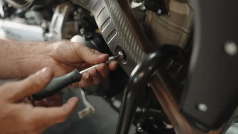 Mechanic using a screwdriver on a motorcycle frame Stock Footage 346182942
