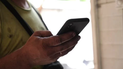 Mechanic using smartphone to check vehicle information in a well-lit garage Video stock 318725041