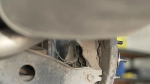 A mechanic using a socket wrench behind a car wheel. Stock Footage 342263333