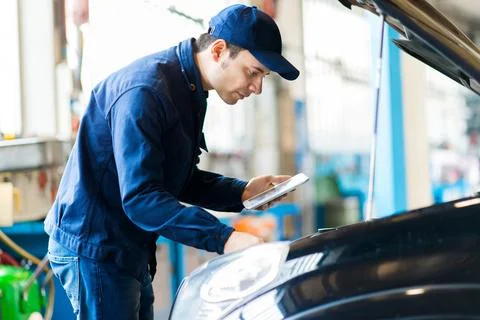 Mechanic using a tablet in his garage Stockfoto's