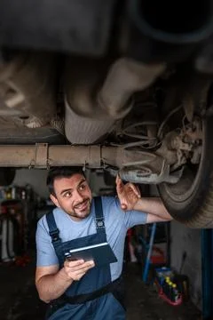 Mechanic using tablet while inspecting car in repair shop Stock Photos