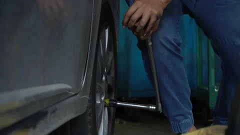 Mechanic using wheel wrench remove and changing wheel on car in workshop at c Stock Footage 147367702