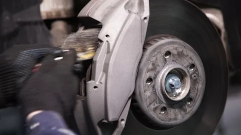 Mechanic using a wire brush cleans the place for car brake pads Stock Footage 72099034