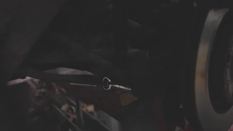 Mechanic using wrench to adjust bolt under vehicle, focused work in dimly lit Stock Footage 275193246