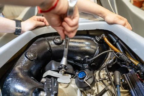 Mechanic using a wrench while repairing a jet ski engine Stock Photos