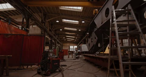 Mechanic welding large metal structure in warehouse Stock Footage 254935661