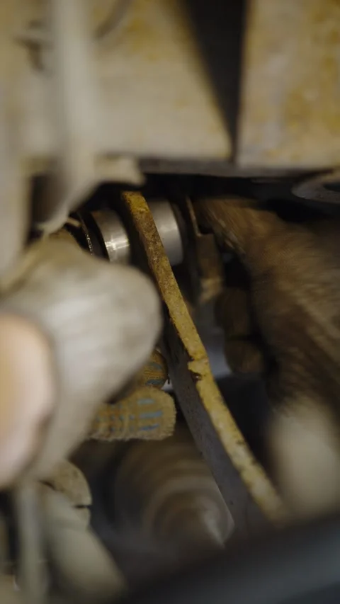 Mechanic in work gloves installs silver bushing into rusty suspension Stock Footage 337569447