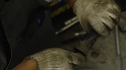 A mechanic in work gloves repairs a metal vehicle part Stock Footage 340154760