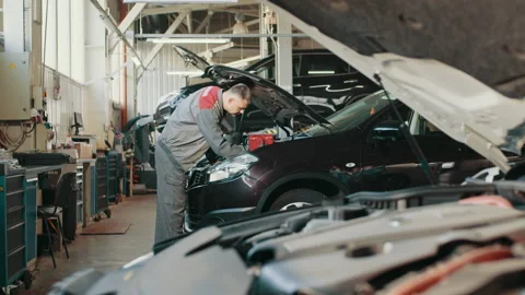 Mechanic at work in his garage. Auto electrician troubleshooting a car engine Stock Footage 180850193