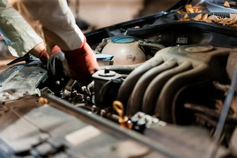 Mechanic Working on Car Engine in Dimly Lit Garage Foto stock