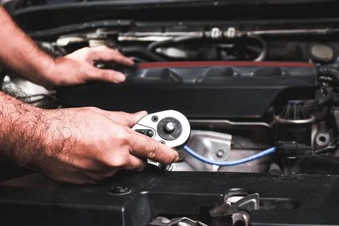 Mechanic working on car engine with tools Stock Photos