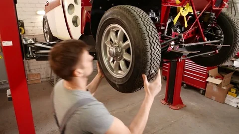 Mechanic working on classic car wheels and suspension in restoration workshop Stock Footage 74634755