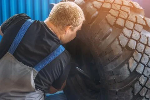 Mechanic Working on Large Tire in Workshop Setting Stock Photos