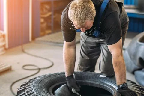 Mechanic Working on a Tire in a Workshop Environment Stock Photos