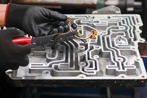Mechanic working on a transmission sensor with wire strippers. Stock Photos