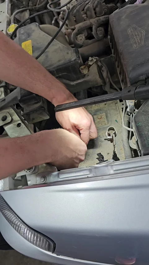 Mechanic works on car engine to fix wiring problem in repair garage Stock Footage 335648823