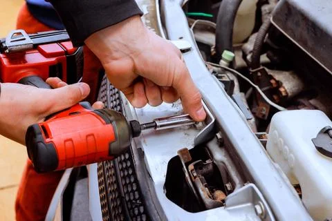 Mechanic works on car engine using power tool in garage 스톡 사진
