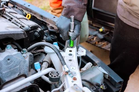 Mechanic works on car headlight, using tool in open garage Foto stock