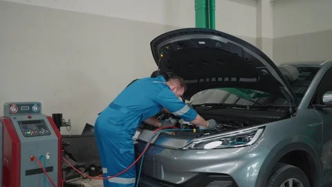 Mechanic works on a EV car with open hood Stock Footage 339050271
